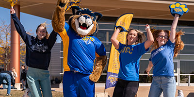 Students jumping happily with Chase Cougar