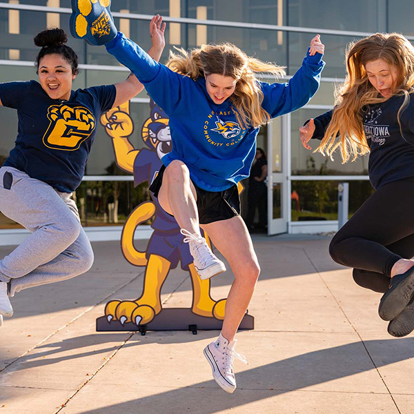 Three NICC students jump for a photograph in front of the Peosta entrance.