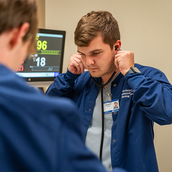 An NICC nursing student adjusts his stethoscope while in the nursing simulation lab.