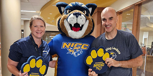 Joni Knopp and Chris Entringer posing for a photo with Chase the Cougar.