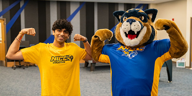 An NICC student flexes with Chase the Cougar.