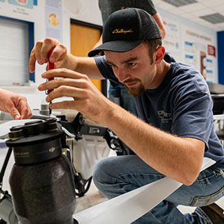 An agriculture student works on a drone.