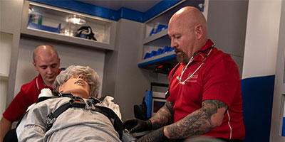 Two EMTs work on a dummy