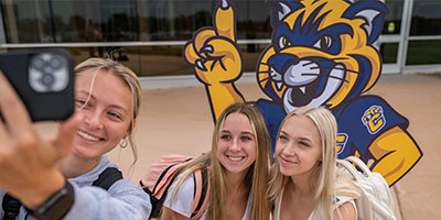 Group of female students taking a selfie with Chase mascot cutout