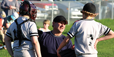 Baseball coach talks to two players