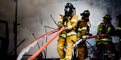 Firefighters working with hose in smoke