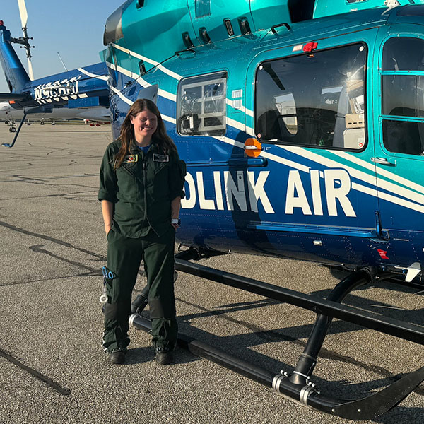 EMT student Tara Kramer posing next to a helicopter.