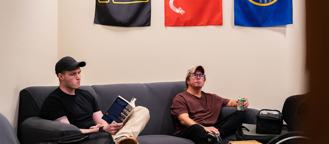 Two military students sit under military flags