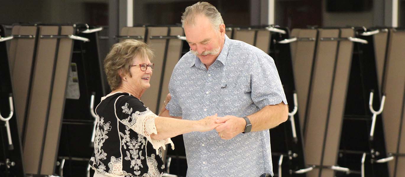 Two older adults dance together