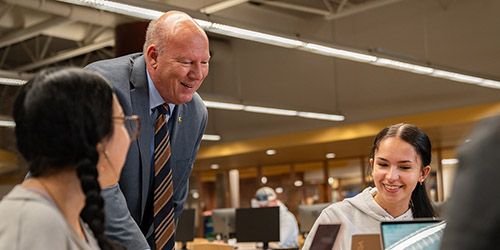 Dave Dahms talking with students in the library.
