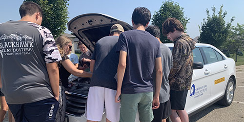 Students and instructor gathered around car