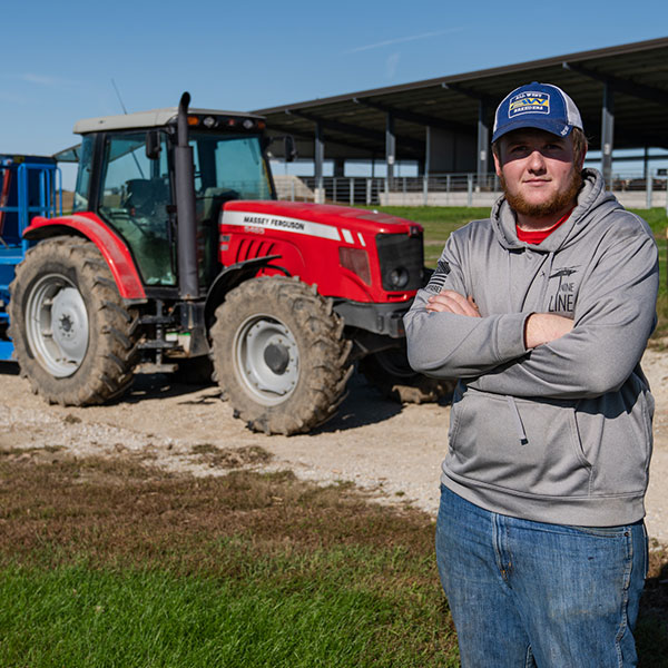 Male Ag student stands in front of a tractor