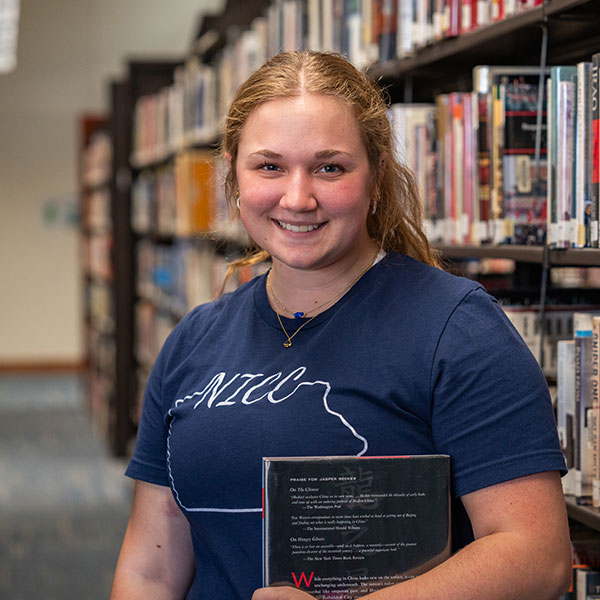 Student poses in library stacks