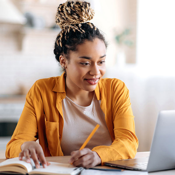 Female professional works on computer and writes down notes