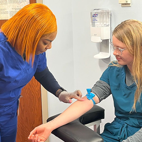 Phlebotomy student practicing on a female patient