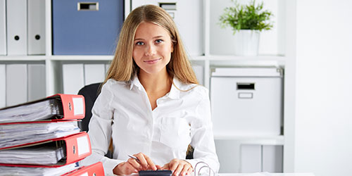 A male accountant reviews invoices at his desk.